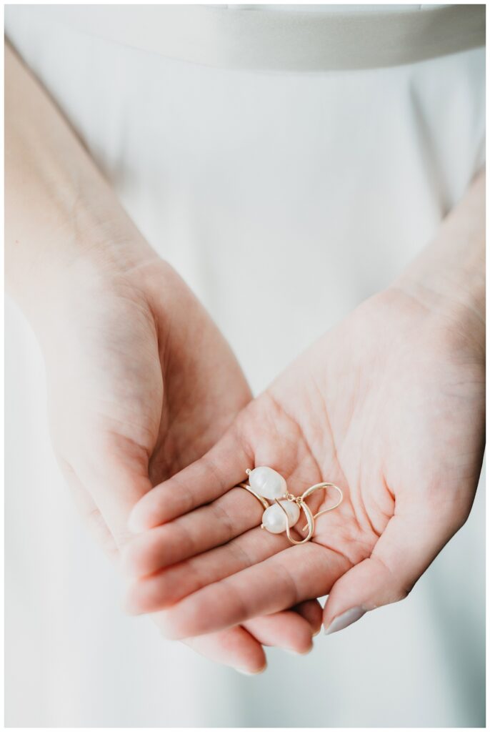 Bride holding earrings in her Detroit Michigan wedding.